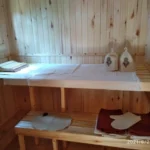 Интерьер русской бани с деревянными стенами, полками для отдыха и текстилем для сауны, включая полотенца и шапки.