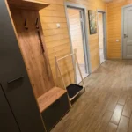 Коридор в деревянном доме с вешалкой и картинами на стенах.